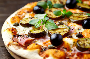 Tasty pizza with grilled zucchini, mozzarella cheese, black olives, capers and fresh herbs. Close up.	