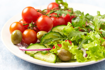Healthy salad with cherry tomatoes, green olives, cucumber, red onion, lettuce and cucumber. 
