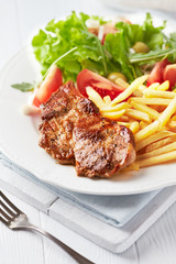 Grilled Steak with french fries and fresh salad. White wooden background.