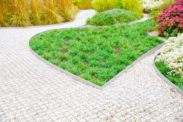 Landscape design, beautiful garden with garden embankments of white stone and curb metal tape with grass and flowers.