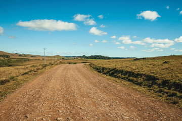 Fototapeta na wymiar Dirt road passing through rural lowlands and ranch