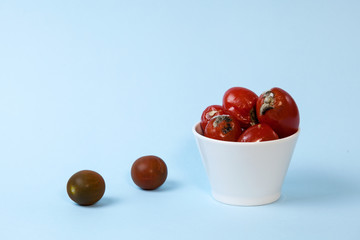 Rotten tomatoes in a bowl on a light blue background.