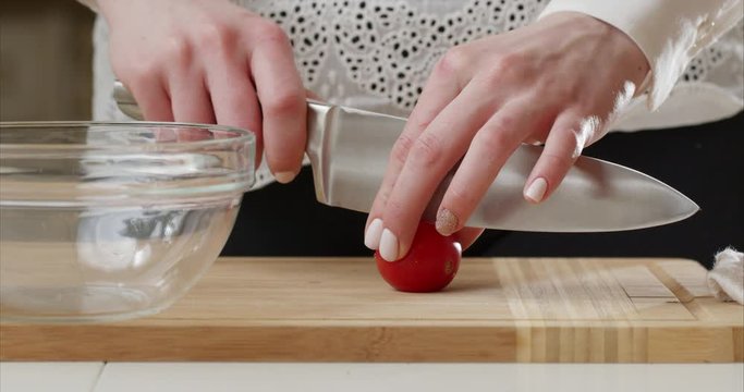 Tomato cutting closeup. Chef slices the cherry tomato. Knife, cutting Board, cherry tomato. The hands of the cook. Cut vegetables for salad. Healthy food. Close-up. Macro.Shot on 6k Blackmagic camera.