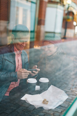 Cute Caucasian couple sitting in a cafe drinking coffee and playing video games on a handheld smartphone device