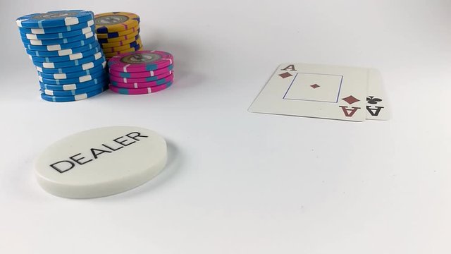 Four aces landing one by one on a white table near a stack of poker chips and dealer button, STILL