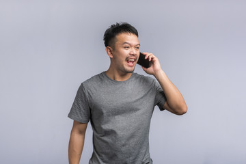 good looking Asian man talking on the phone, getting goods news,excited happy.