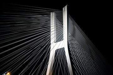 A large bridge with steel cables glows brightly at night