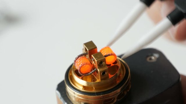 A man inserts new cotton wool in an electronic brown cigarette