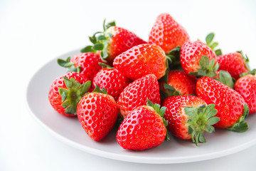 Fresh strawberries on a light grey plate, on a white background