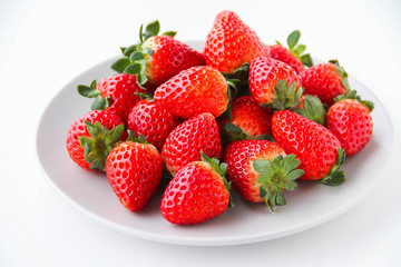 Fresh strawberries on a light grey plate, on a white background