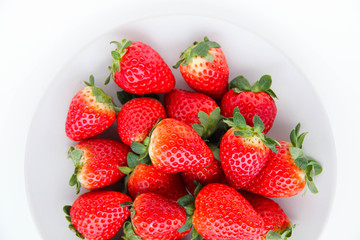 Fresh strawberries on a light grey plate, on a white background