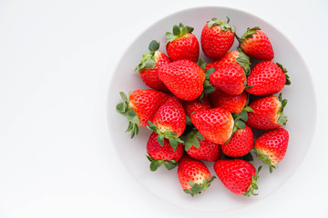 Fresh strawberries on a light grey plate, on a white background
