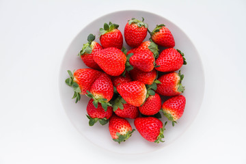 Fresh strawberries on a light grey plate, on a white background