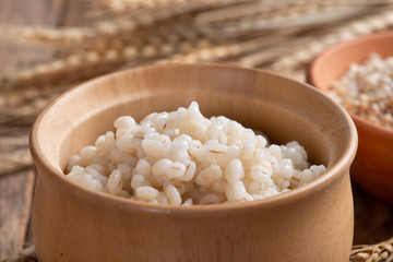 Cooked peeled barley grains in wooden bowl