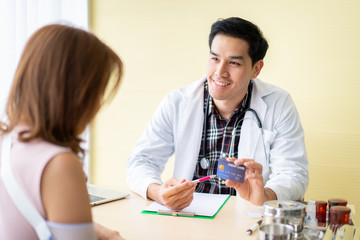 Asian doctor showing a credit card (fake credit card) to patient.  Healthcare and insurance concept.