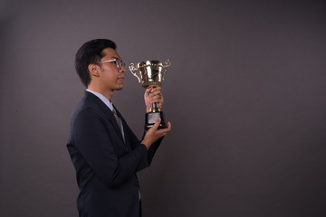 Happy young male intrepreneur or business man holding his gold trophy and celebrating his victory.Studio shot.