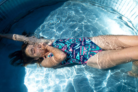 A girl submerges underwater in a small outdoor tub pool