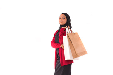 Happy young Muslim girl holding shopping bags isolated over white background.