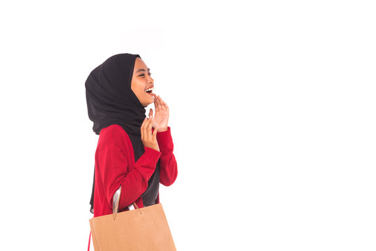 Happy young Muslim girl holding shopping bags isolated over white background WITH COPY SPACE.