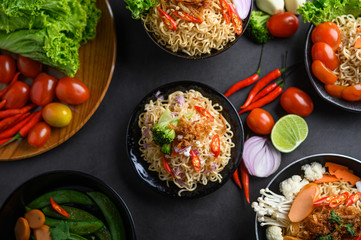 Noodles spicy in the bowl with ingredients on black cement background, Top view.