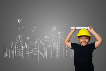 A boy wearing a yellow engineer hat and a house plan on a blackboard