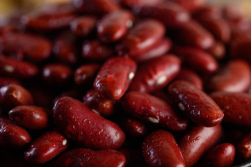 Red beans in a wooden bowl and with water sprayon the black cement floor.