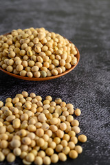Yellow beans in a wooden bowl on the black cement floor.