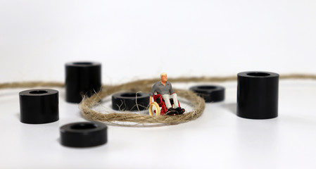 A miniature man in a wheelchair with a rope.