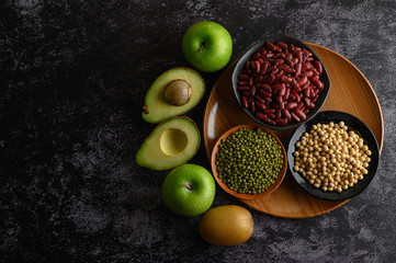 legumes and fruit on a black cement floor background.
