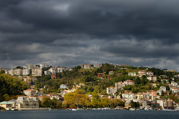 Fototapeta na wymiar Bebek harbour Istanbul with storm clouds and sun over apartments on hill and Egyptian Consulate