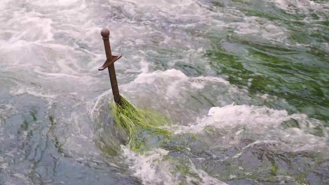 CHEDDAR, SOMERSET, ENGLAND, December 28, 2019: Sword  in the middle of a water stream. King Artur and the round table. Excalibur legend.