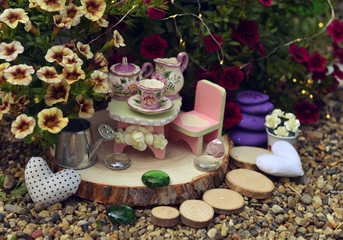 Fun tea party with small furniture and dishware in the garden.