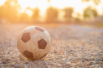 Fototapeta na wymiar Old and dirty classic soccer ball at the countryside in the morning