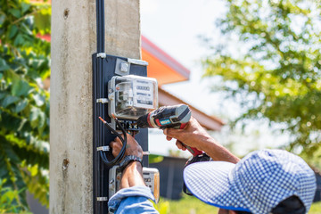 Technician installing electric meter on the pole