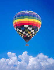 Naklejka premium Aerial view of a multicolored hot air balloon flying on blue sky.