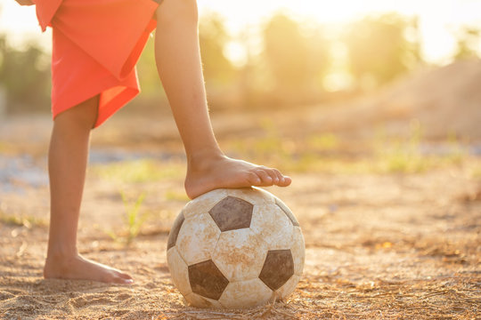 Young Asian Boy Playing Old And Dirty Classic Soccer Ball In The Morning