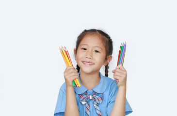 Cheerful little child girl in school uniform holding color pencils over white background. Education and school concept.
