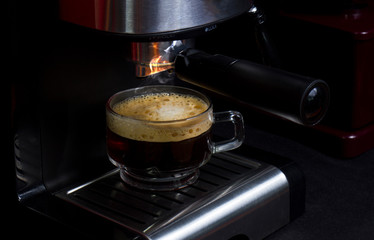 Hot espresso flows into the cup. Making espresso in a clear glass coffee cup
