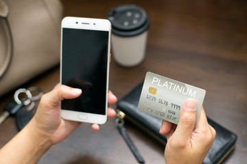 Asian woman using a mobile phone for online transaction with credit card. Copy space blank on the mobile phone screen.