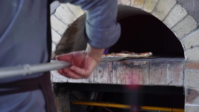 Chef putting pizza to charcoal stove, Medium shot making pizza slowmotion