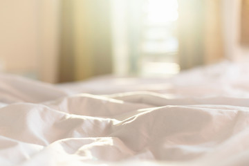 White bedding sheets and pillow in hotel room at morning time with sunlight from windows - obrazy, fototapety, plakaty