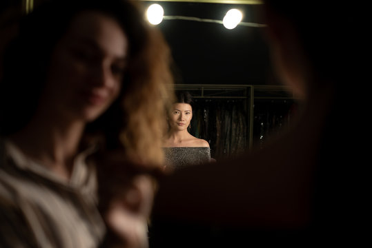 Woman make-up artist in the foreground, in the background focused photo of the model