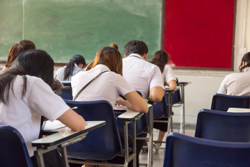 blur focus.front view abstract background of examination room with undergraduate students inside. university student in uniform sitting on lecture chair taking final exam or study in classroom.