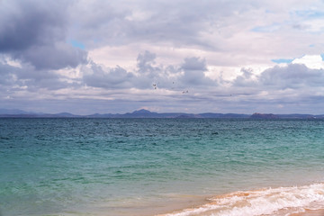 A Flock Of Birds Against A Stormy Sky Above A Tropical Island