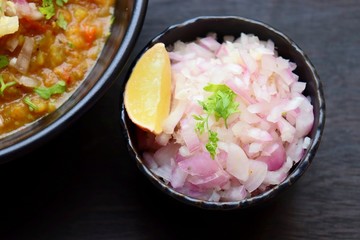 Indian Mumbai Street style Pav Bhaji, garnished with raw onions, coriander and Butter. Spicy thick curry made of out mixed vegetables, served with Bread