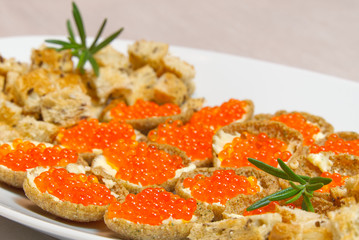 Sandwiches with red caviar on white palte close up