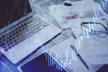 Stock market graph on background with desk and personal computer. Double exposure. Concept of financial analysis.