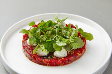 watermelon tartare decorated with mint leaves, herbs, laid out on a plate
