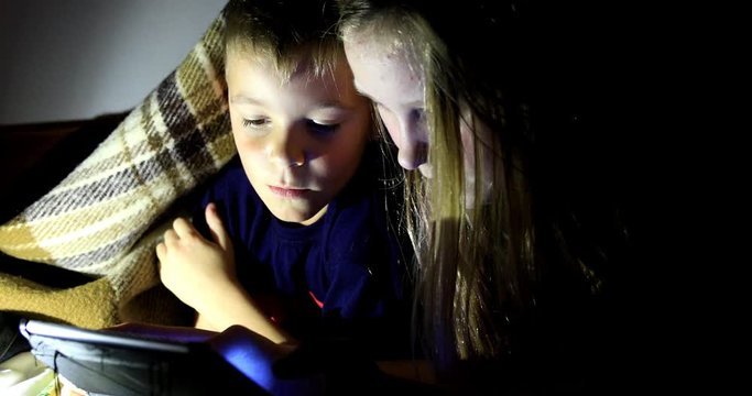 Little girl and boy watching content on her smartphone. The pitfalls of social networks. The childern secretly communicates over the Internet at night. Viewing inappropriate content.