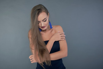 Fototapeta premium Woman with beauty long brown hair, posing at studio. long earrings classic blue